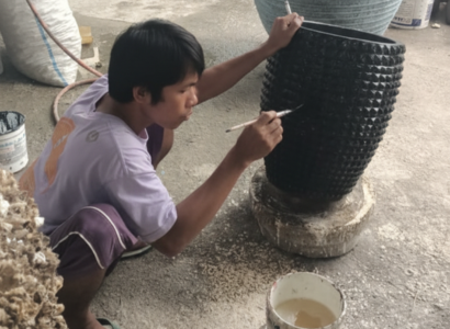 Artisan balinais peignant à la main un grand vase décoratif dans un atelier