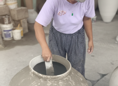 Artisan balinais appliquant une finition sur un grand vase en céramique.