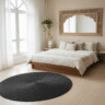 Tapis de sol rond en tressage serré de couleur noir charbon, au centre d'une chambre à coucher au style minimaliste bohème.