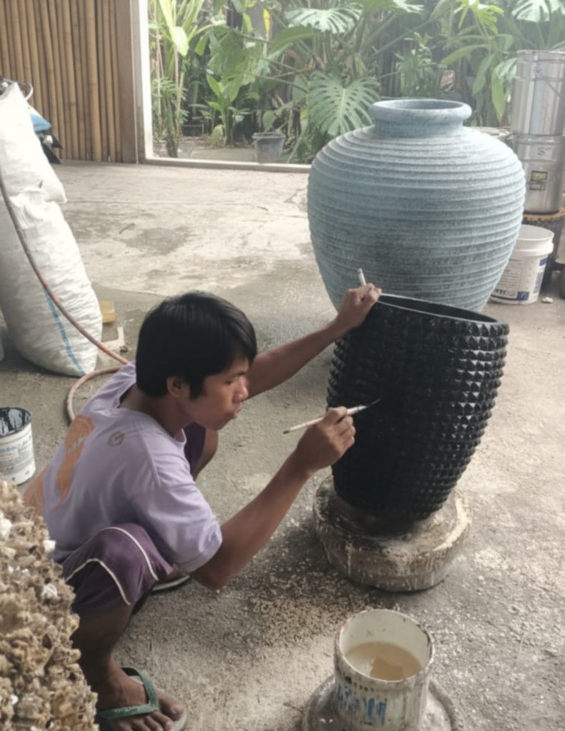 Artisan balinais peignant à la main un vase décoratif, illustrant le savoir-faire traditionnel et la fabrication artisanale à Bali.