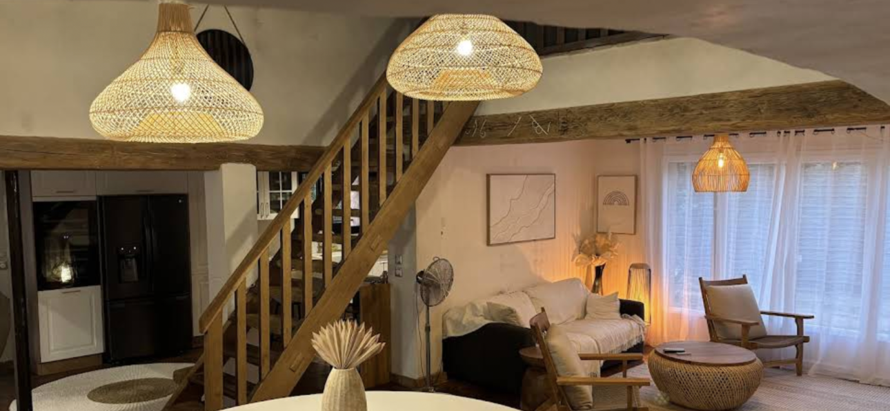 Salon bohème chic avec suspensions en rotin, mobilier en bois naturel et décoration aux matières naturelles.