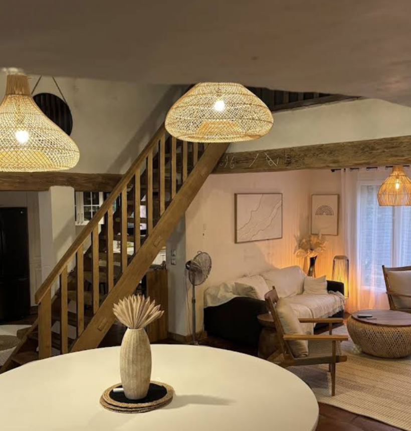 Salon bohème chic avec suspensions en rotin, mobilier en bois naturel et décoration aux matières naturelles.